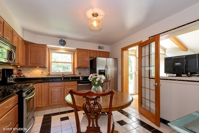 999 Shermer Road Northbrook, IL 60062 - Photo 6 of 17 a kitchen with a table chairs refrigerator and microwave