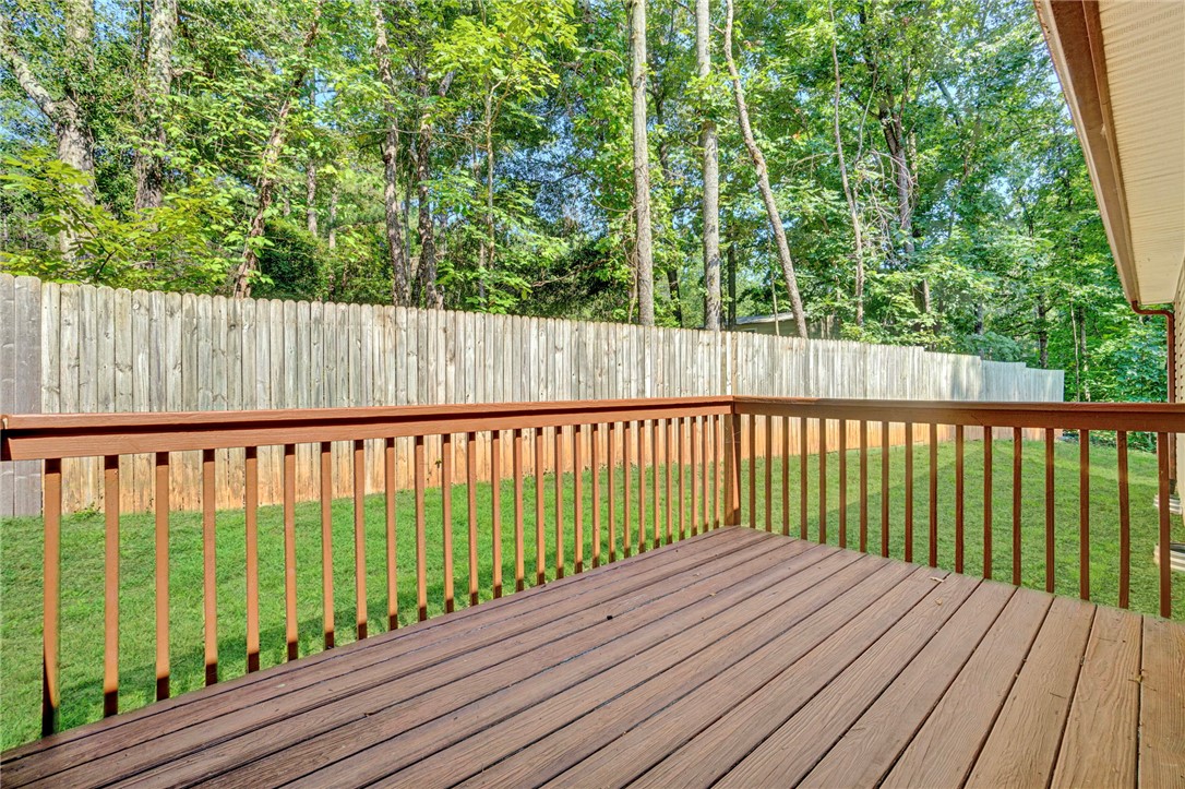 114 Summersweet Lane Seneca, SC 29672 - Photo 9 of 25 An elevated wooden deck overlooks a grassy backyard enclosed by a tall privacy fence.