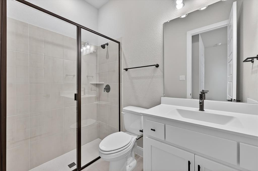 2237 Pika Road Northlake, TX 76247 - Photo 35 of 37 Contemporary bathroom featuring a framed glass shower enclosure, white subway tile shower surround, and a built-in shower shelf