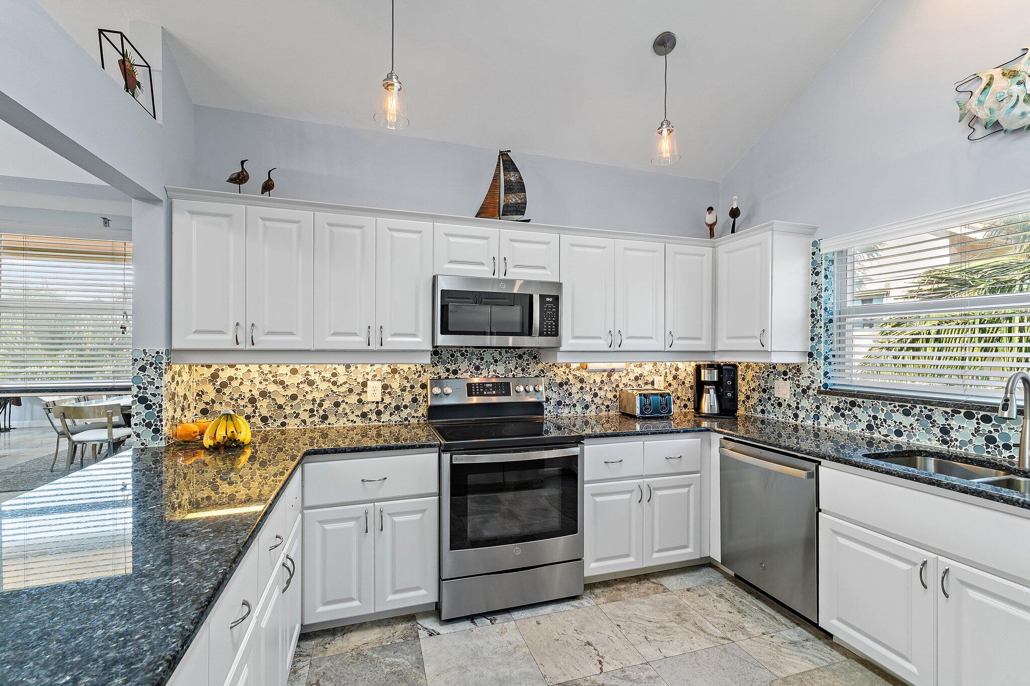 4161 U.S. Highway 1, Unit G3 Jupiter, FL 33477 - Photo 9 of 71 a kitchen with stainless steel appliances granite countertop a stove a sink and a microwave