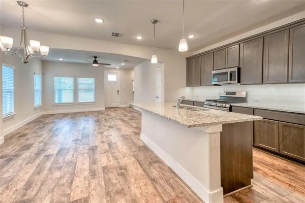 a kitchen with kitchen island granite countertop a sink cabinets and stainless steel appliances
