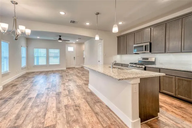 a kitchen with kitchen island granite countertop a sink cabinets and stainless steel appliances