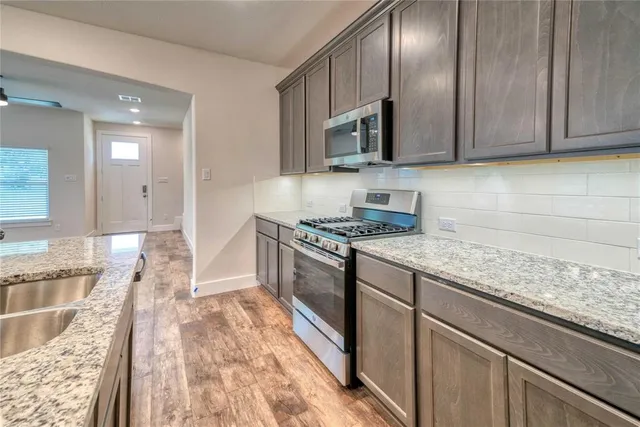 a kitchen with stainless steel appliances granite countertop a sink stove and microwave
