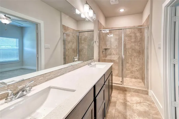 a spacious bathroom with a granite countertop sink a shower and a mirror