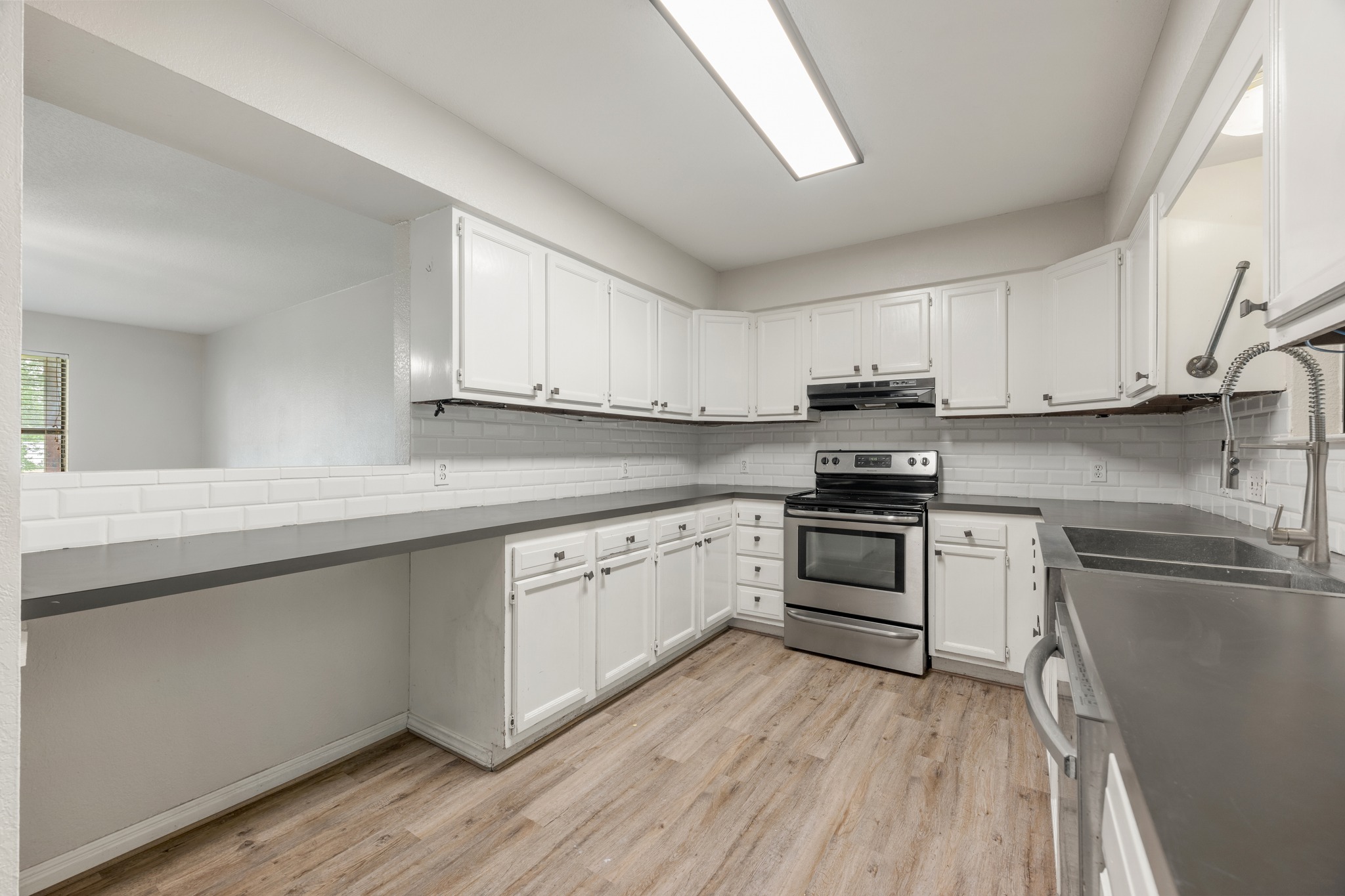 110 Skyview Terrace Leander, TX 78641 - Photo 12 of 26 Kitchen featuring white cabinetry, subway tile backsplash, stainless steel appliances, wood-finish flooring, and a pass-through window