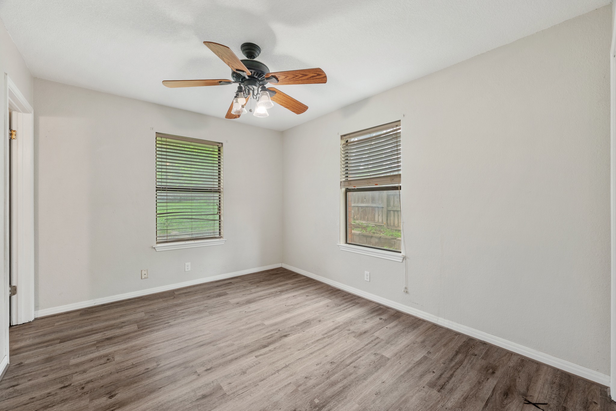 110 Skyview Terrace Leander, TX 78641 - Photo 15 of 26 Interior room featuring wood-finish flooring, two windows with blinds, a ceiling fan with light fixture, and neutral painted walls