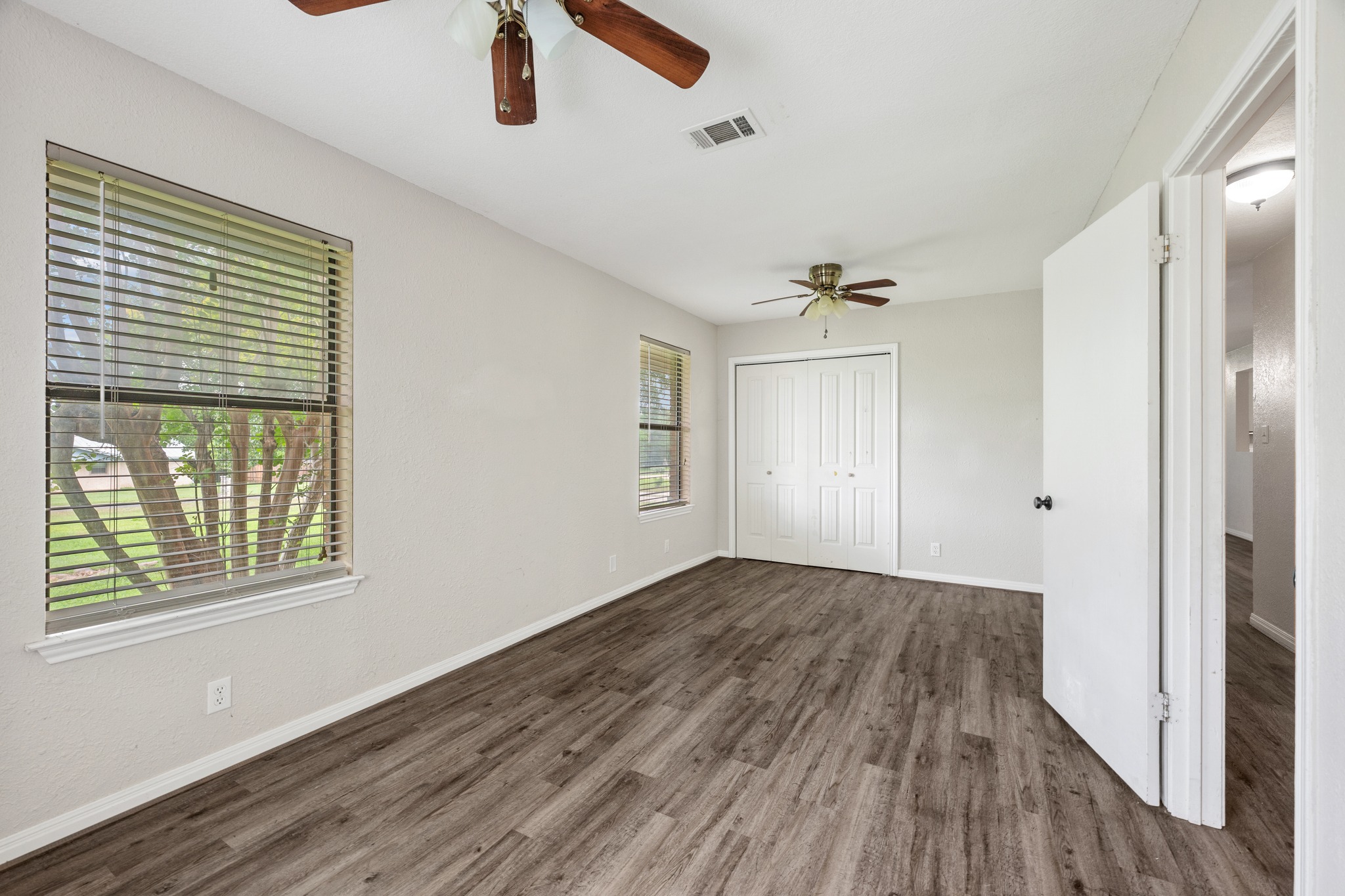 110 Skyview Terrace Leander, TX 78641 - Photo 19 of 26 Spacious room featuring wood-finish flooring, two windows with blinds, dual ceiling fans, and a bi-fold closet door