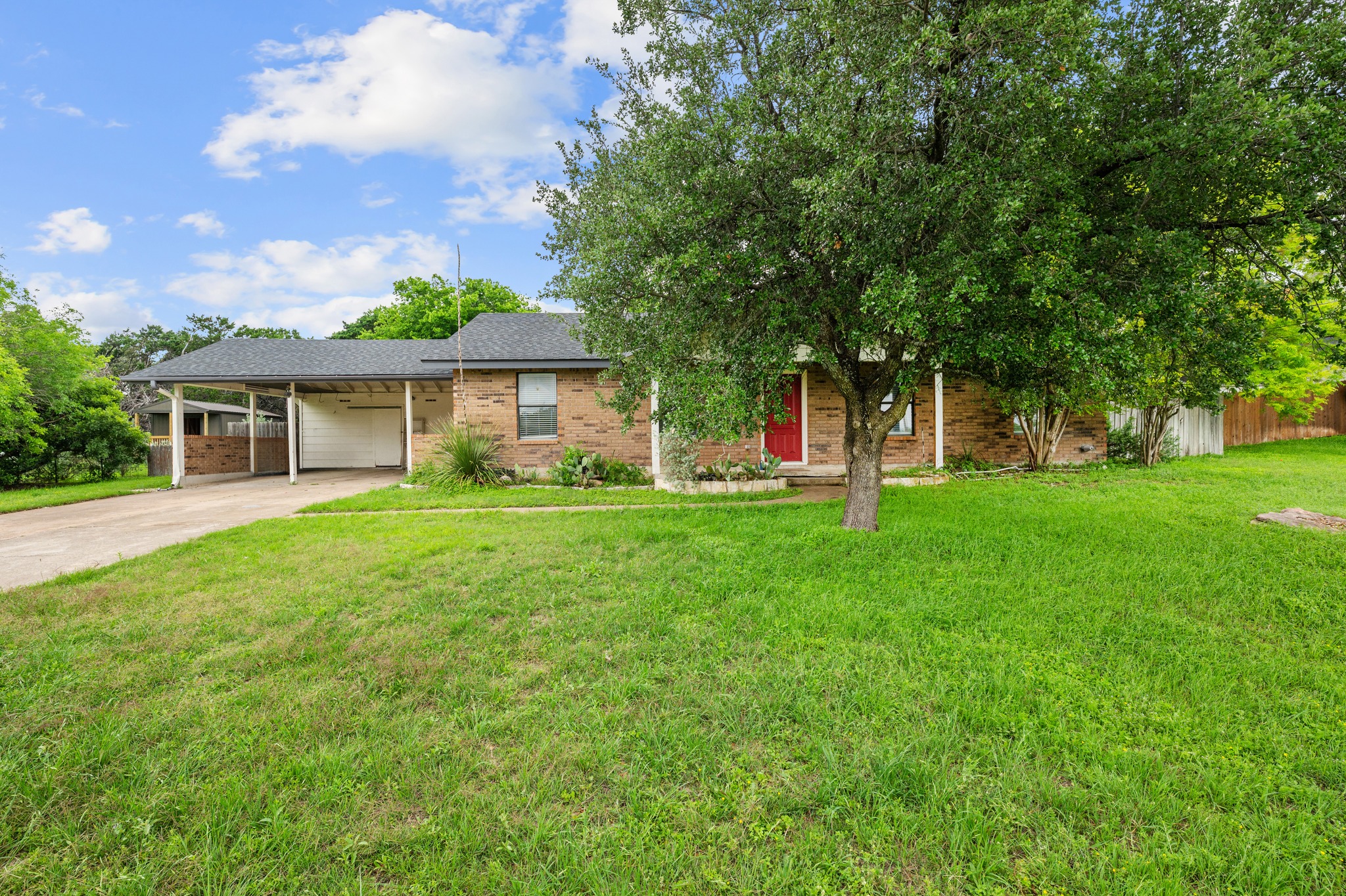 110 Skyview Terrace Leander, TX 78641 - Photo 2 of 26 Brick exterior residence featuring a covered carport, attached garage, and a lush green lawn