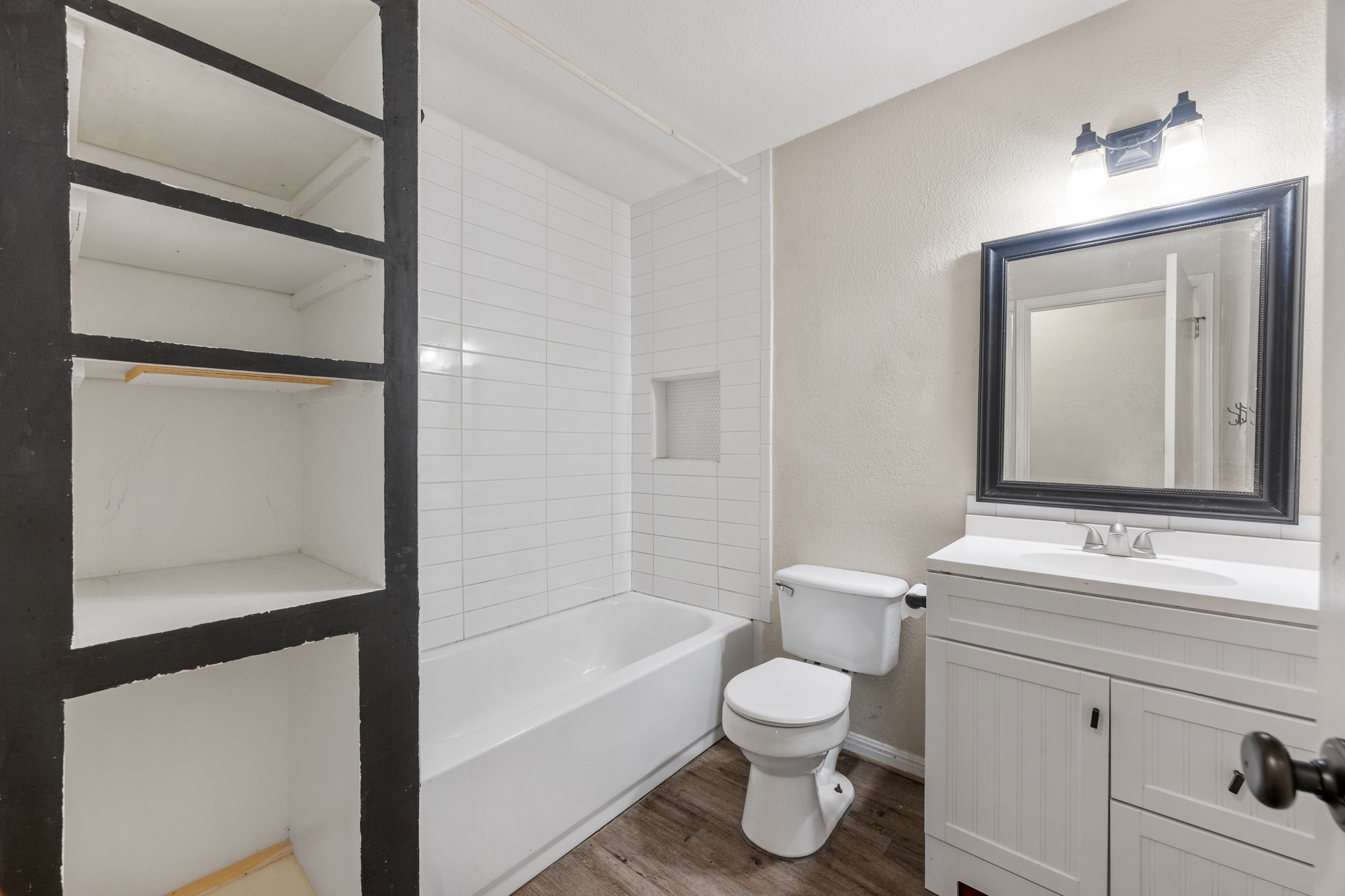 110 Skyview Terrace Leander, TX 78641 - Photo 21 of 26 Full bathroom featuring a white vanity with a white countertop and rectangular mirror, a white toilet, a white bathtub with subway tile surround, and built-in shelving
