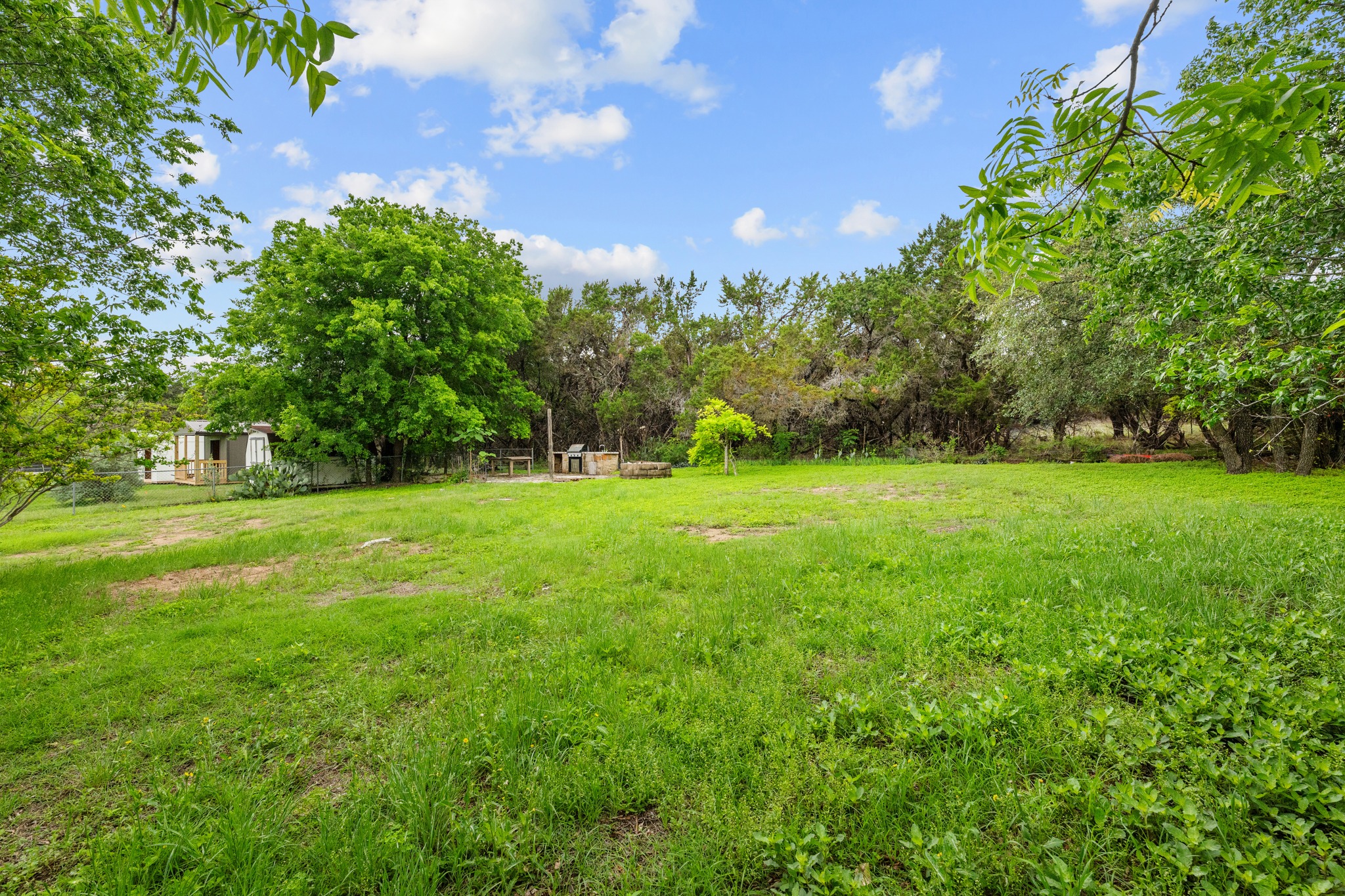110 Skyview Terrace Leander, TX 78641 - Photo 23 of 26 Expansive green lawn surrounded by mature trees, featuring a detached shed and a built-in outdoor cooking station