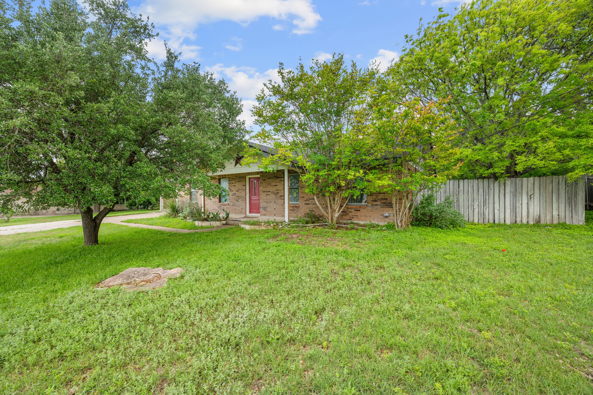 110 Skyview Terrace Leander, TX 78641 - Photo 4 of 26 Brick facade home featuring a prominent mature tree and a vibrant green lawn