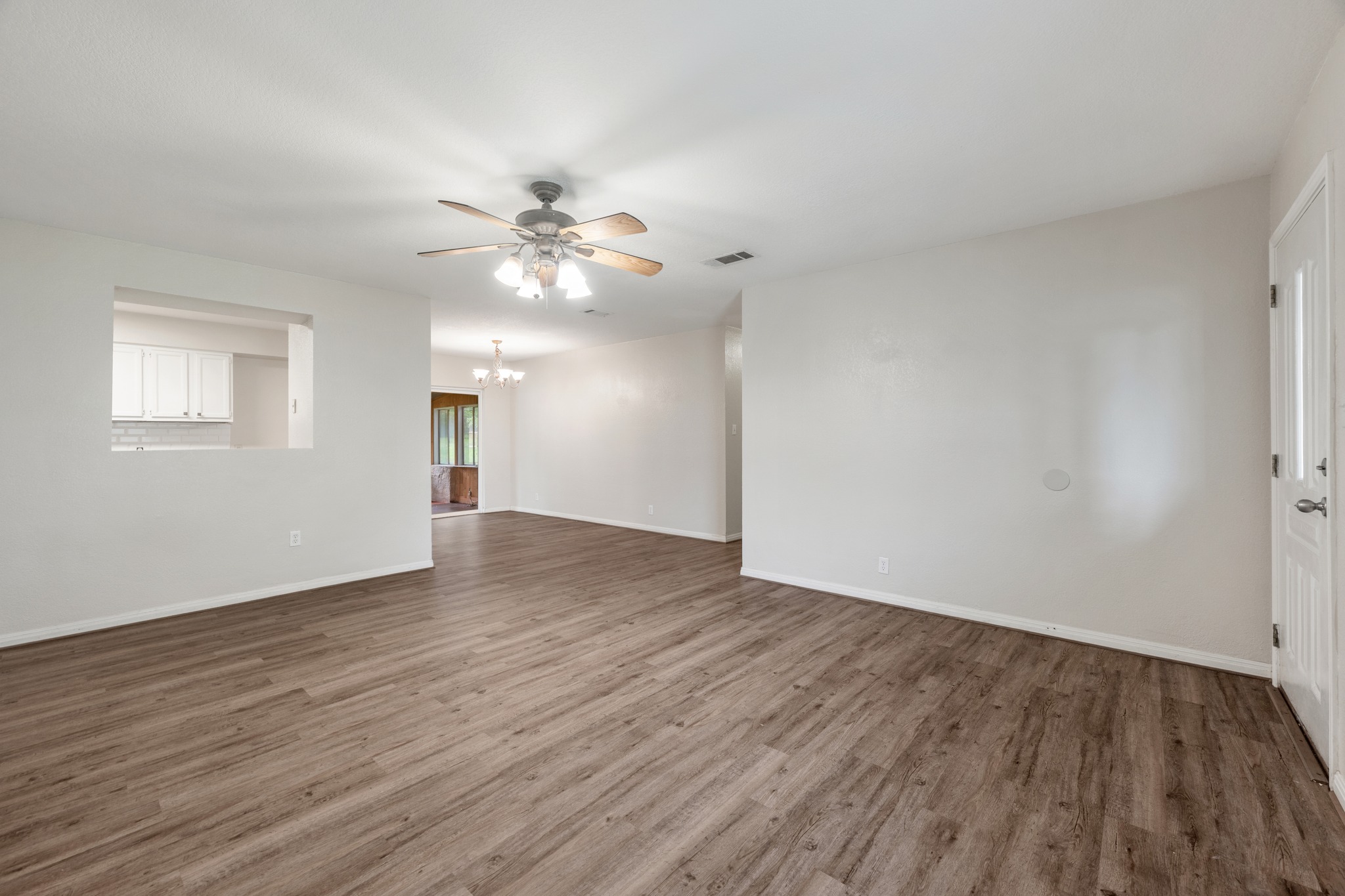 110 Skyview Terrace Leander, TX 78641 - Photo 7 of 26 Spacious living area featuring wood-finish flooring, a ceiling fan with integrated lighting, and a pass-through window to the kitchen