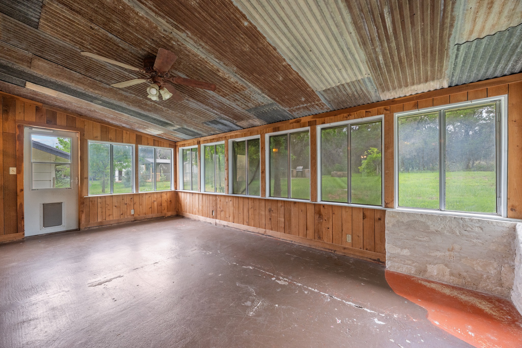 110 Skyview Terrace Leander, TX 78641 - Photo 9 of 26 Spacious screened-in porch featuring a corrugated metal ceiling, wood-paneled walls, and a ceiling fan