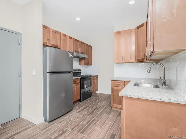 a kitchen with granite countertop stainless steel appliances a refrigerator a sink and cabinets