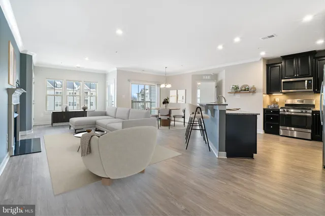 a living room with stainless steel appliances furniture and a wooden floor