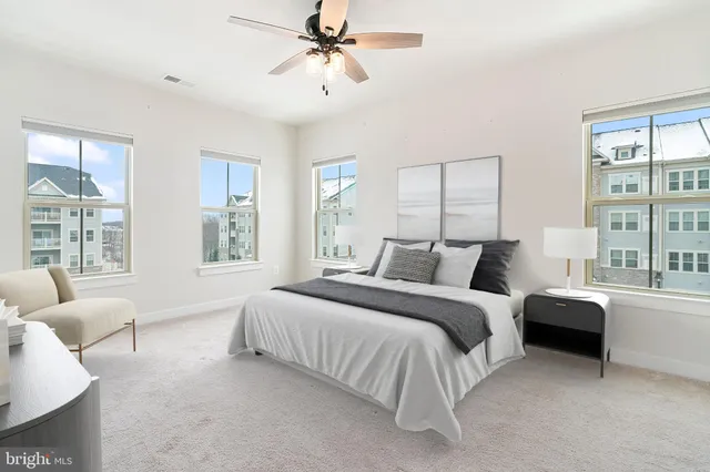 a spacious bedroom with a bed a couch and large window