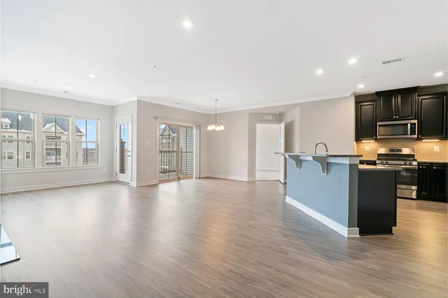 a view of kitchen with stainless steel appliances wooden floor and large window