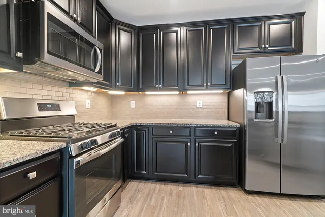 a kitchen with granite countertop a refrigerator stove and cabinets