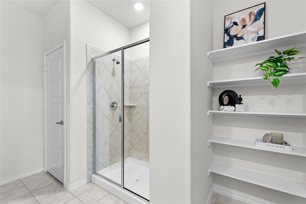 2908 Frio Road Little Elm, TX 75068 - Photo 16 of 26 Enclosed shower with clear glass door, tiled surround, built-in shower niche, and chrome fixtures