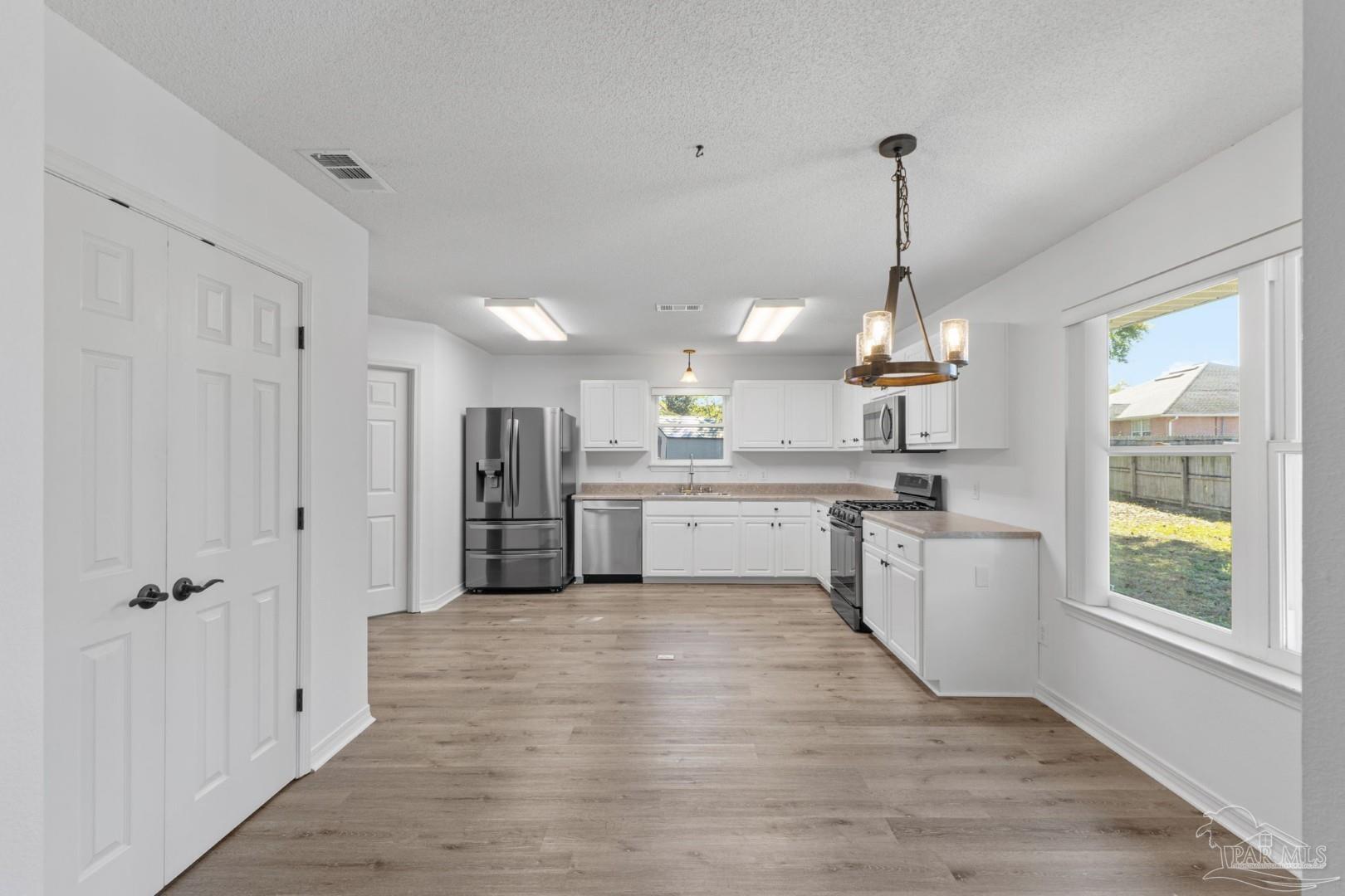 11841 Old Course Road Cantonment, FL 32533 - Photo 14 of 46 a large kitchen with kitchen island a stove a sink dishwasher a refrigerator and white cabinets with wooden floor