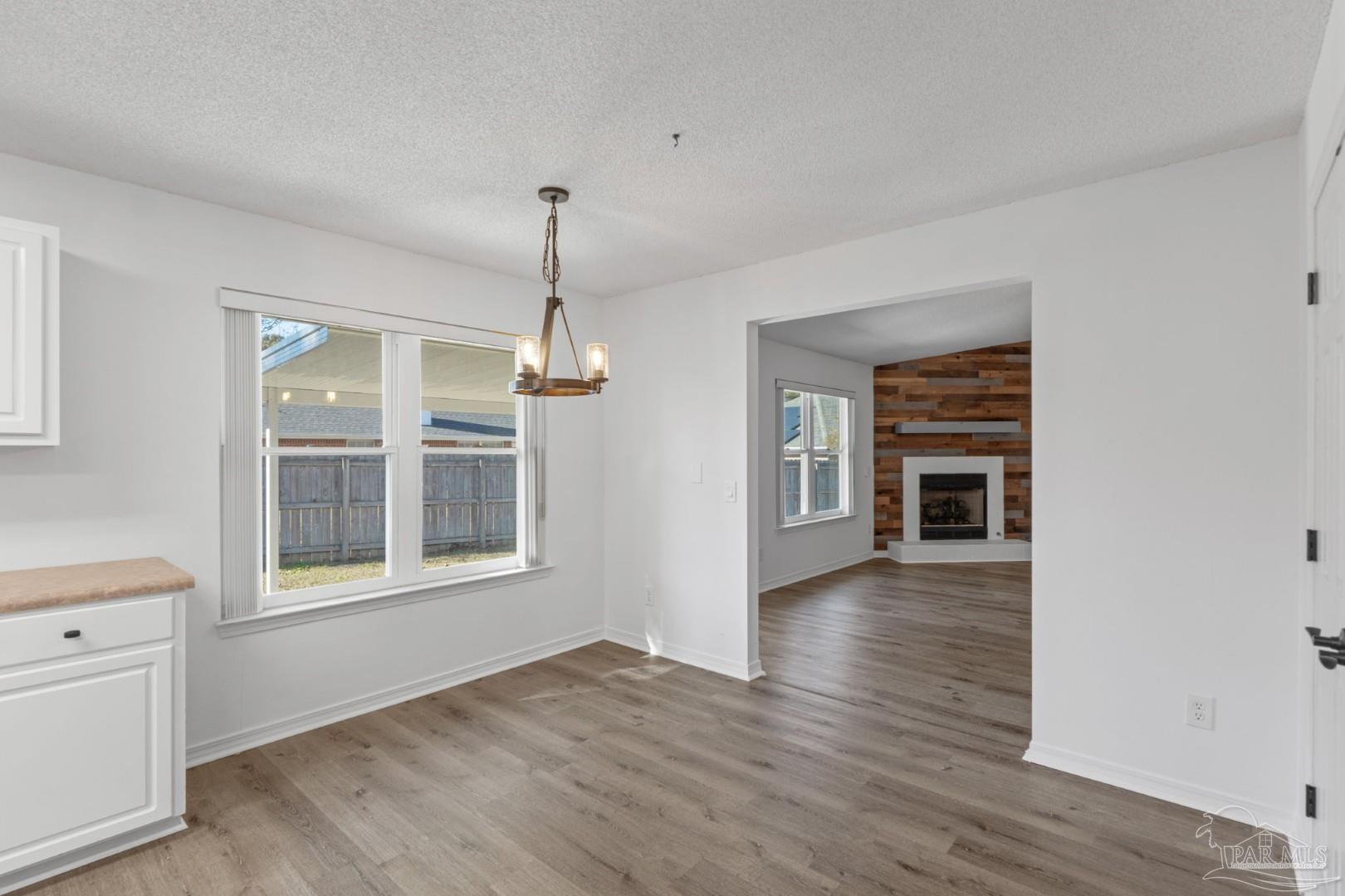11841 Old Course Road Cantonment, FL 32533 - Photo 15 of 46 an empty room with wooden floor chandelier and windows