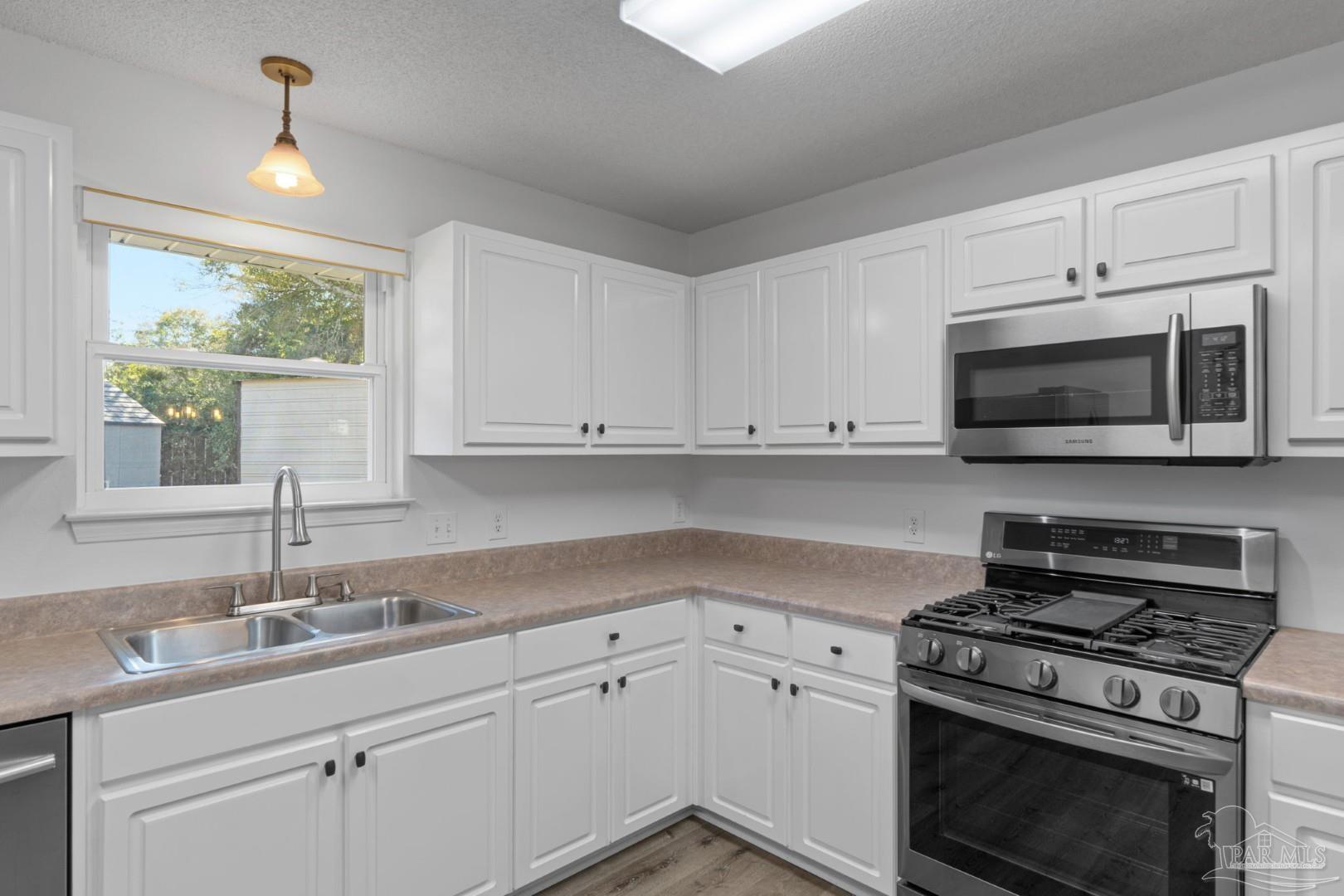 11841 Old Course Road Cantonment, FL 32533 - Photo 18 of 46 a kitchen with cabinets stainless steel appliances a sink and a window