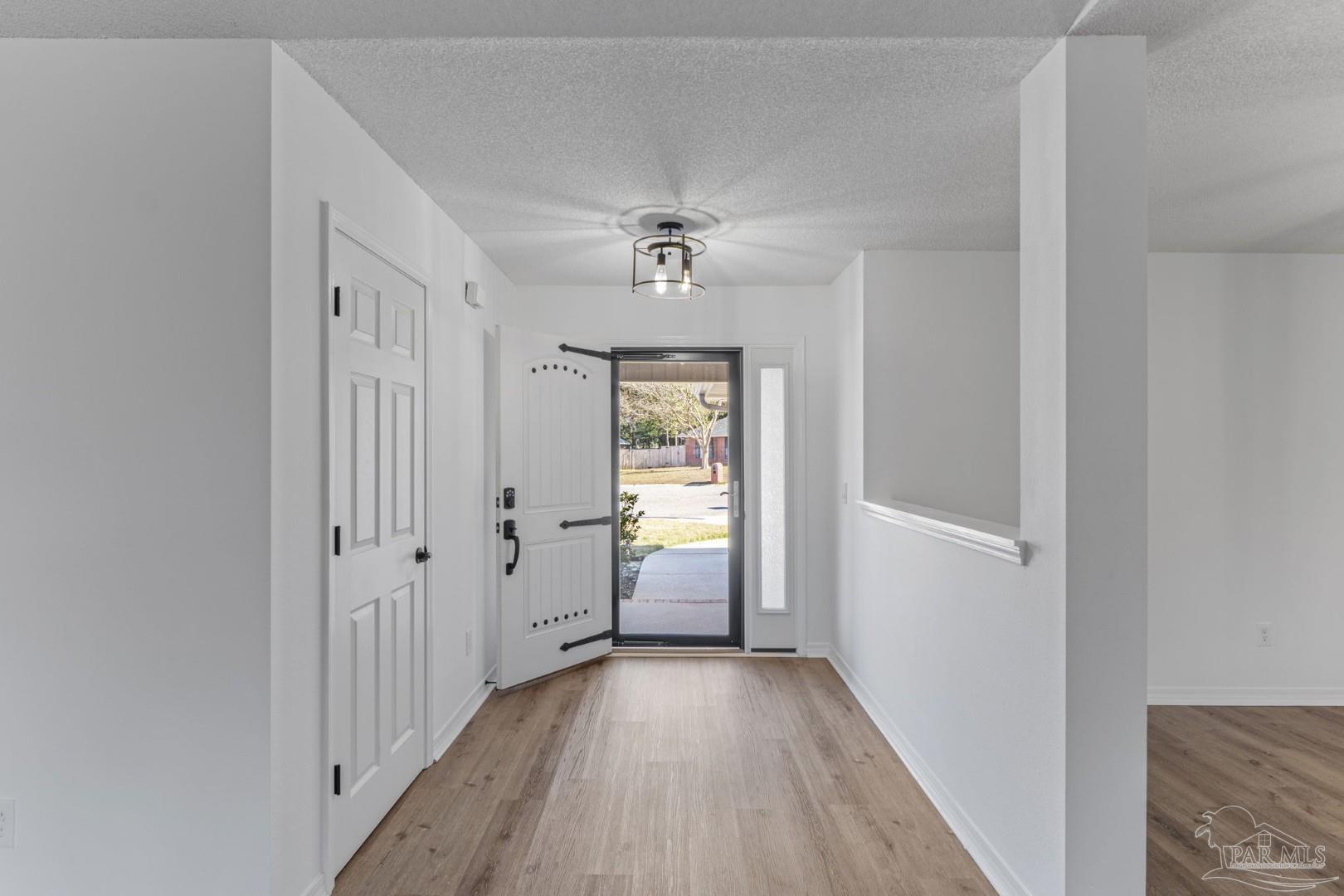 11841 Old Course Road Cantonment, FL 32533 - Photo 5 of 46 a view of a hallway with wooden floor and a chandelier