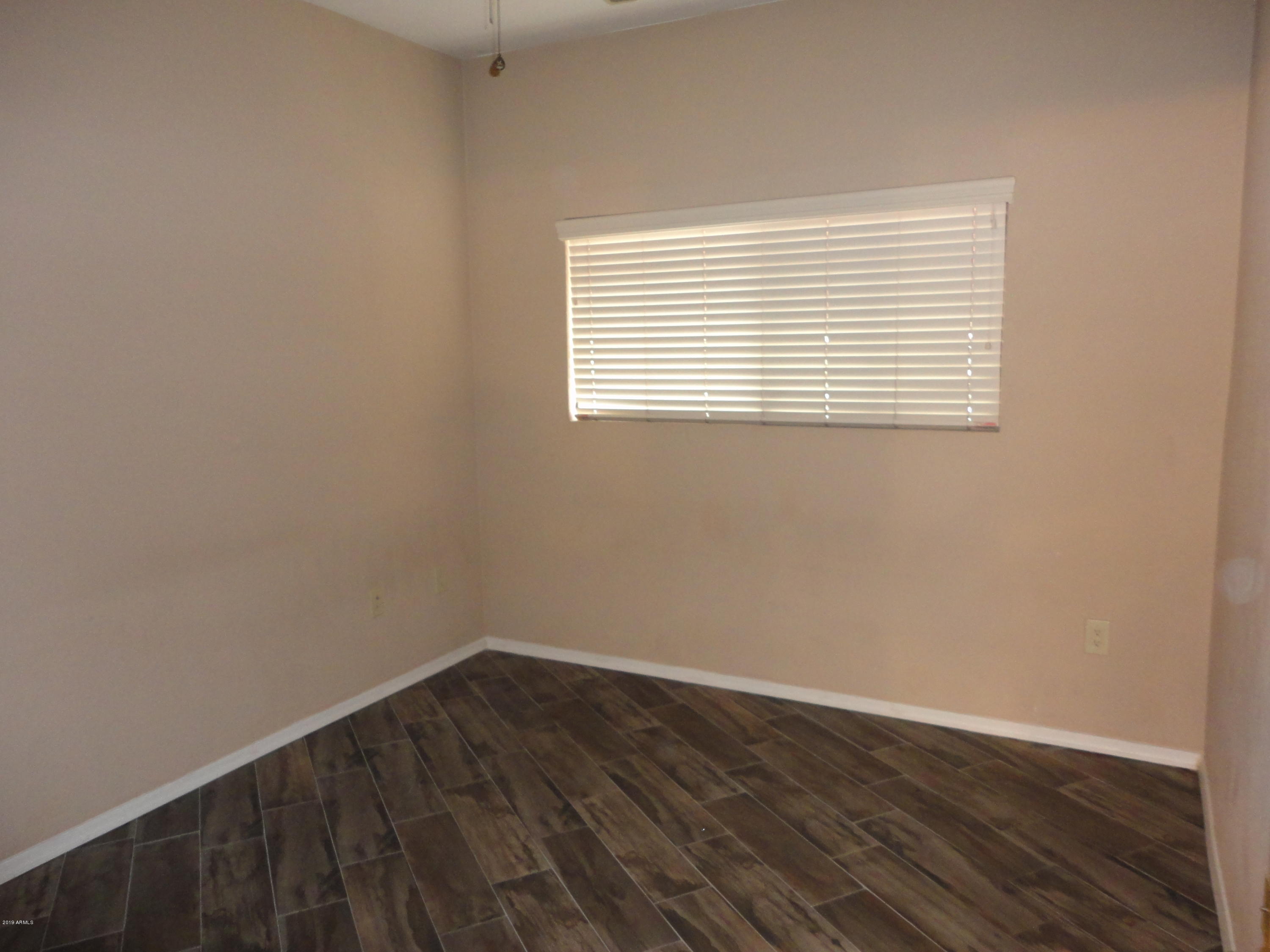 3434 East Baseline Road, Unit 166 Phoenix, AZ 85042 - Photo 4 of 13 wooden floor in an empty room with a window