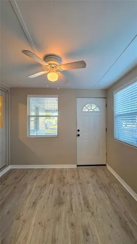 a view of an empty room with window and wooden floor