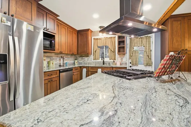 a kitchen with stainless steel appliances granite countertop a refrigerator a stove a sink and a microwave