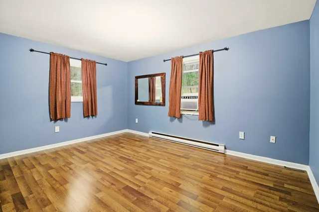 a view of an empty room with window and wooden floor