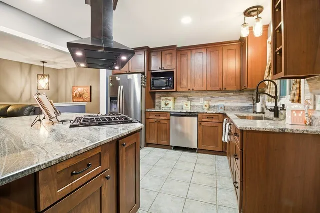 a kitchen with stainless steel appliances granite countertop a sink a stove and a refrigerator