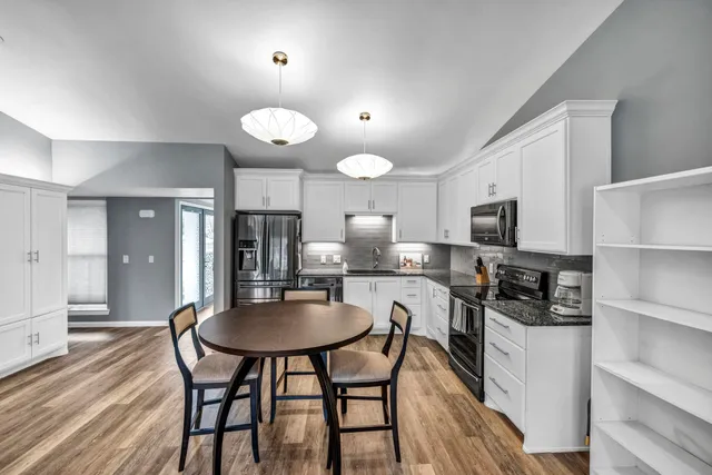 a kitchen with stainless steel appliances a dining table chairs stove and cabinets
