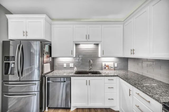 a kitchen with granite countertop white cabinets and stainless steel appliances