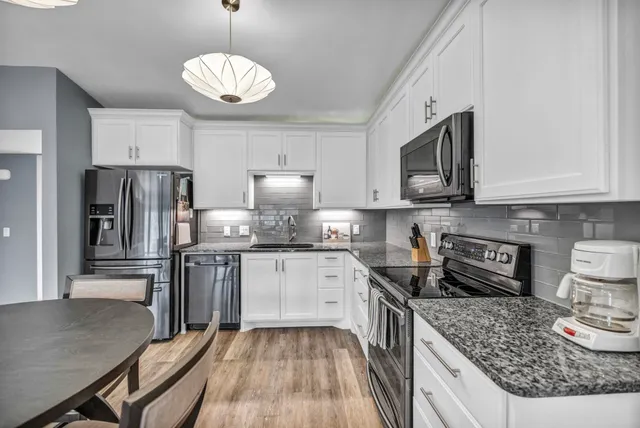 a kitchen with stainless steel appliances granite countertop a stove top oven a refrigerator a sink and dishwasher