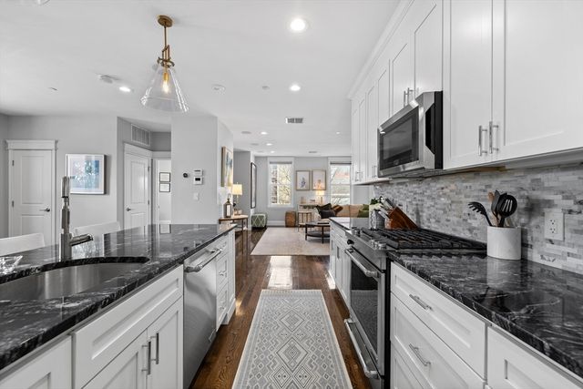 a kitchen with granite countertop a sink a counter top space appliances and cabinets