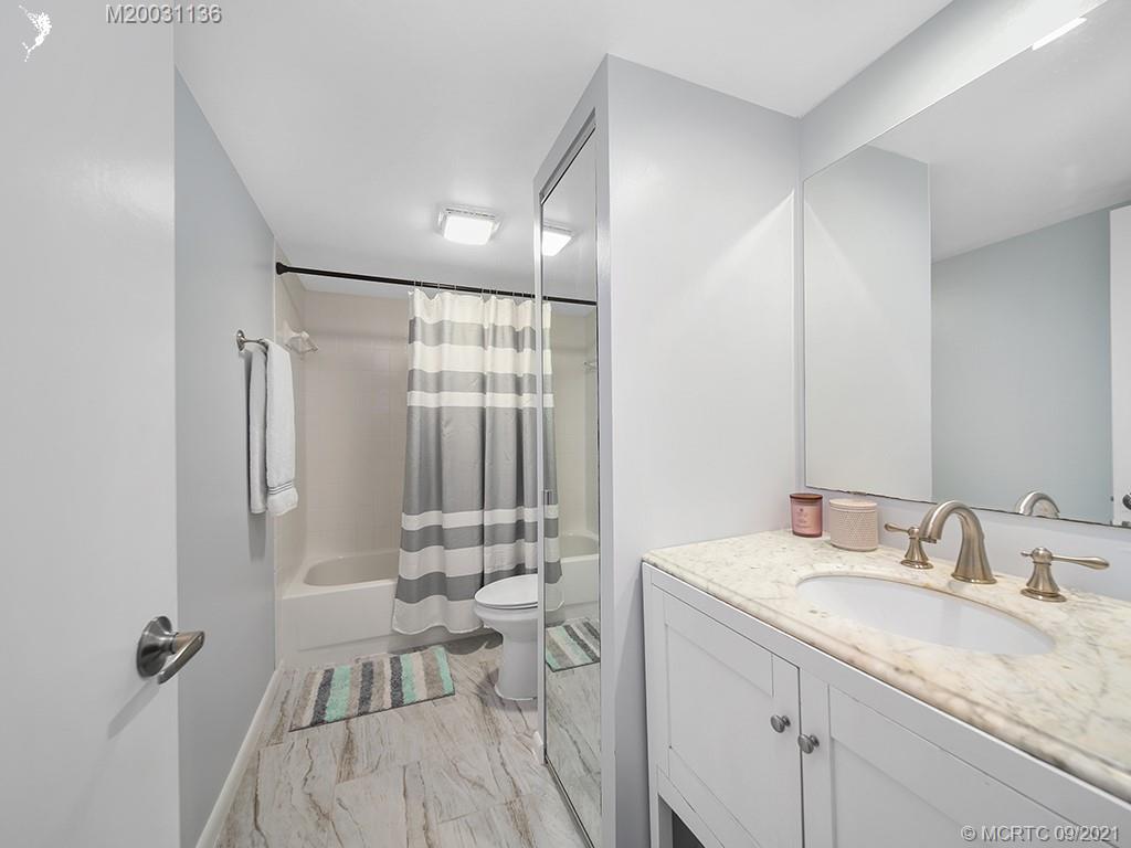 5804 Southeast Windsong Lane Stuart, FL 34997 - Photo 12 of 20 a bathroom with a granite countertop sink a toilet and shower