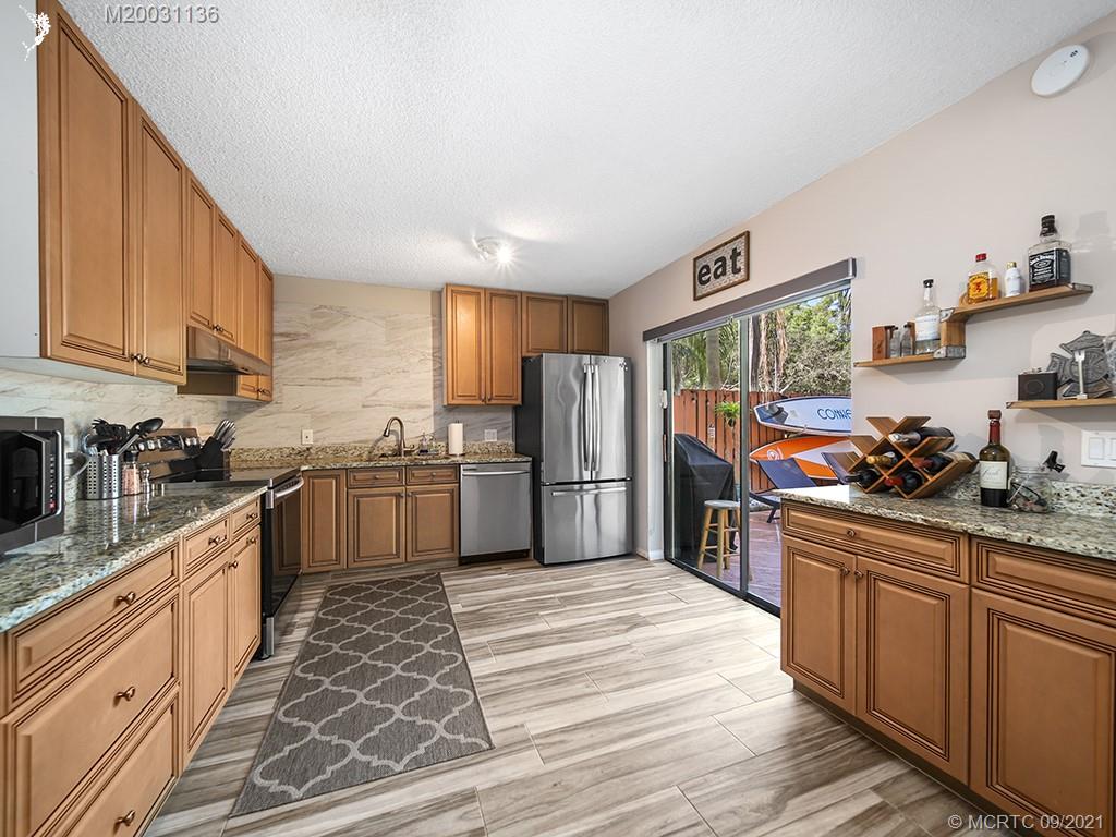 5804 Southeast Windsong Lane Stuart, FL 34997 - Photo 2 of 20 a kitchen with stainless steel appliances granite countertop a stove refrigerator and cabinets