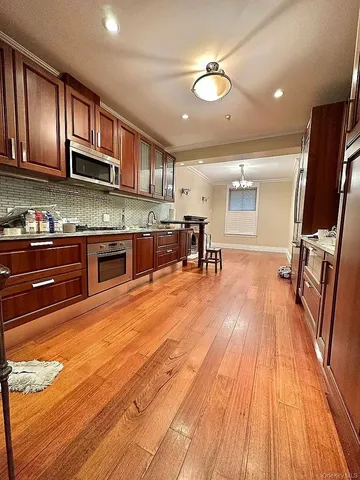 a large kitchen with stainless steel appliances granite countertop a stove and a wooden floors
