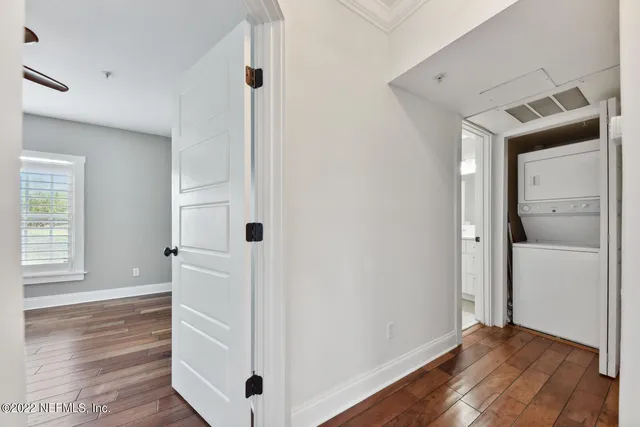 a view of an empty room with window and wooden floor