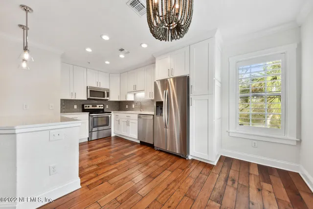 a kitchen with granite countertop white cabinets and stainless steel appliances