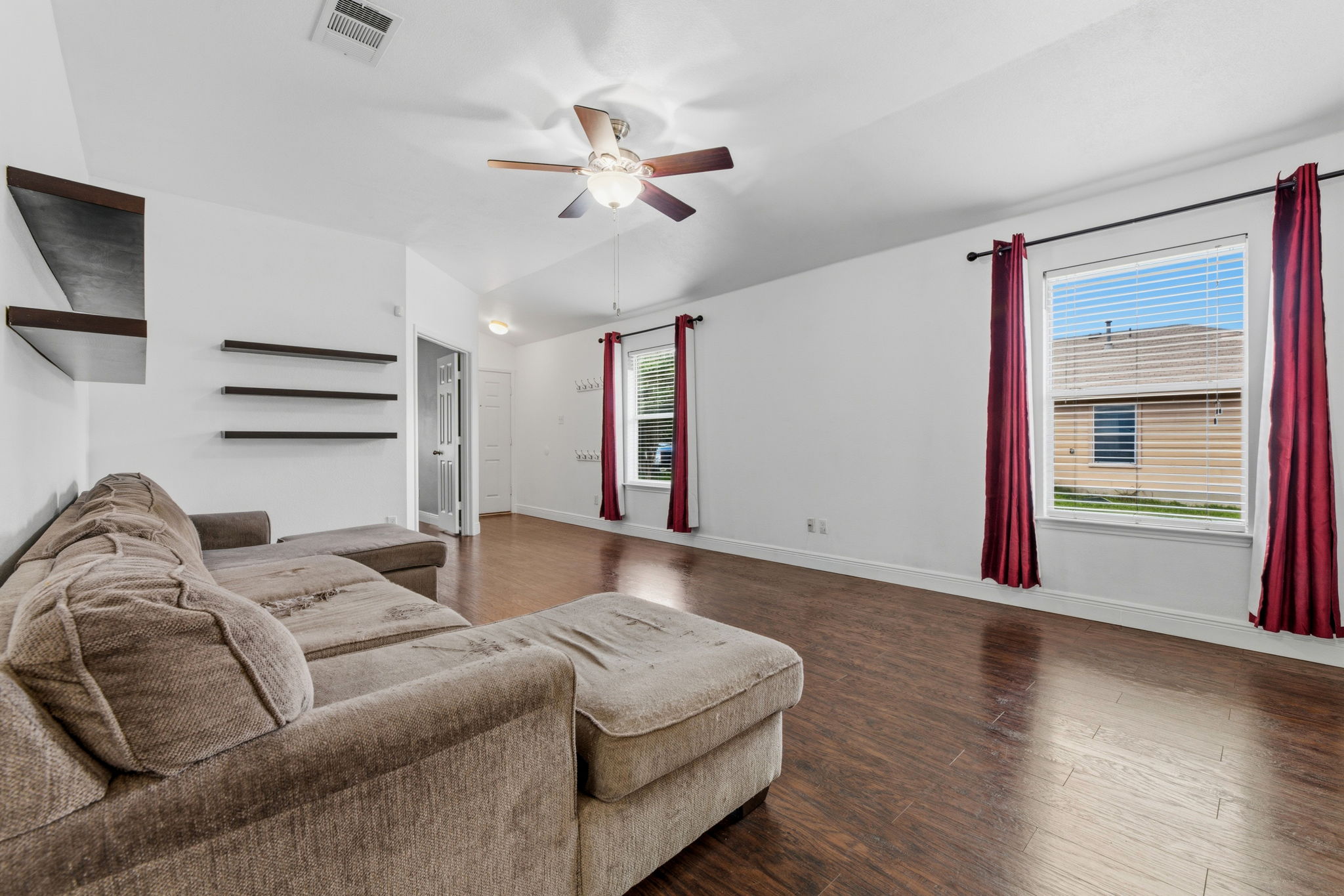 12601 Waynespur Lane Elgin, TX 78621 - Photo 12 of 38 A spacious living area features rich hardwood flooring and an overhead fan for comfort.