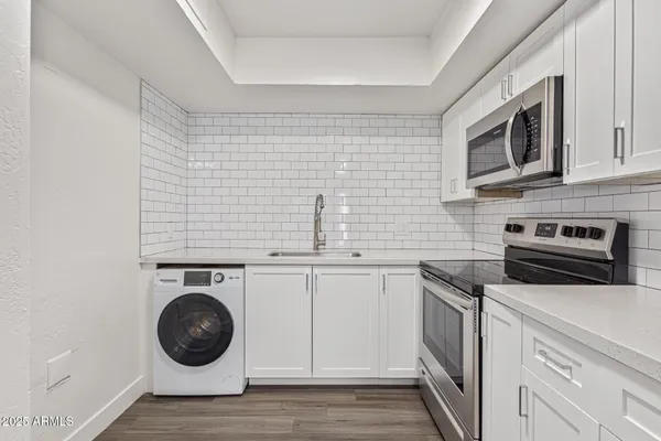 a kitchen with cabinets stainless steel appliances and wooden floor