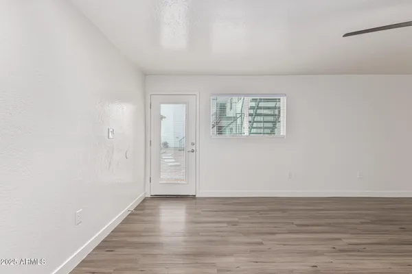 a view of an empty room with wooden floor and a window