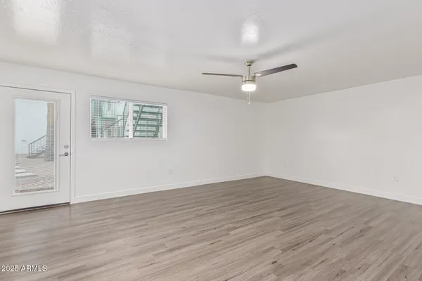 an empty room with wooden floor ceiling fan and windows