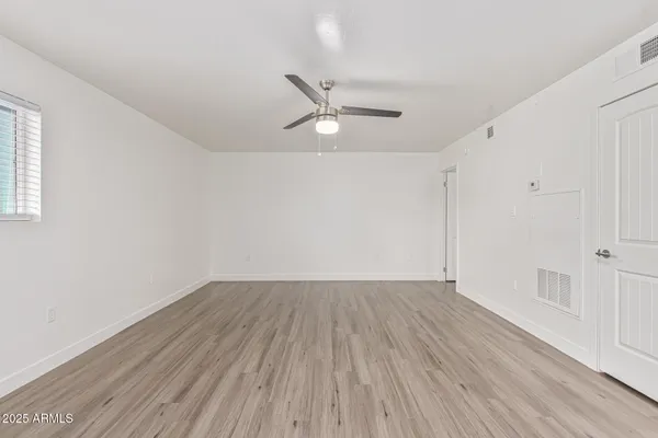 an empty room with wooden floor ceiling fan and windows