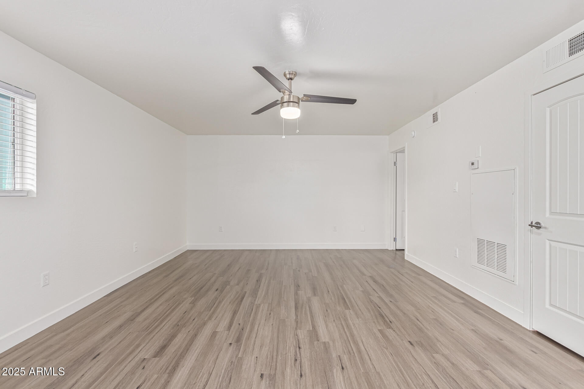 2539 North 48th Street Phoenix, AZ 85008 - Photo 20 of 26 an empty room with wooden floor ceiling fan and windows