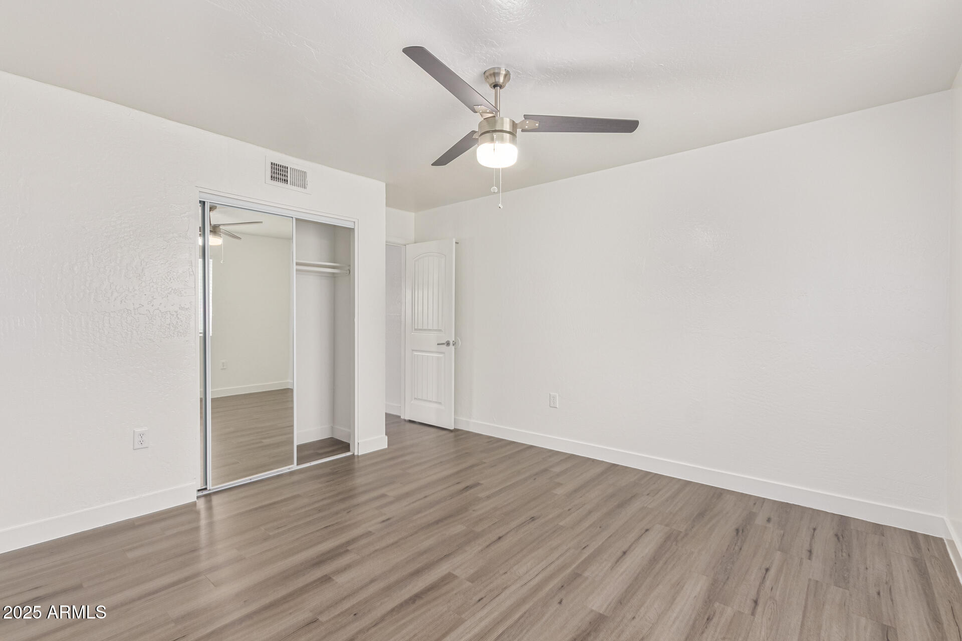 2539 North 48th Street Phoenix, AZ 85008 - Photo 26 of 26 an empty room with wooden floor a ceiling fan and staircase