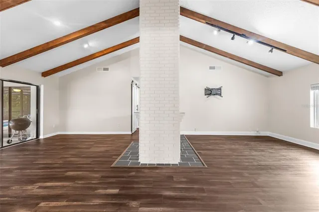a view of empty room with wooden floor and fireplace