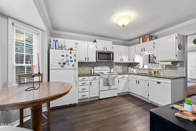 a kitchen with white cabinets stainless steel appliances and a dining table